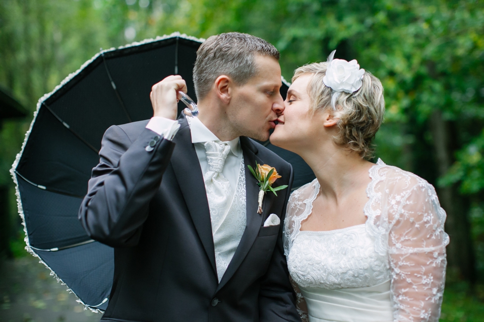 Photo Brautpaar küsst sich unter Regenschirm